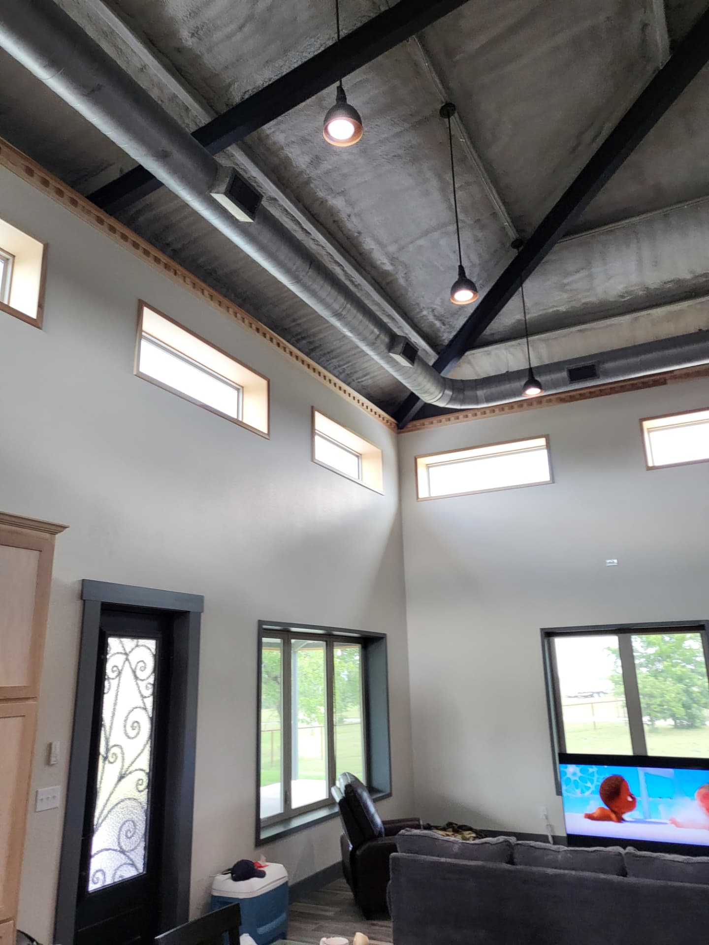 Freshly painted off-white walls with dark framed windows and black steel beams in a high ceiling Johnson County living room