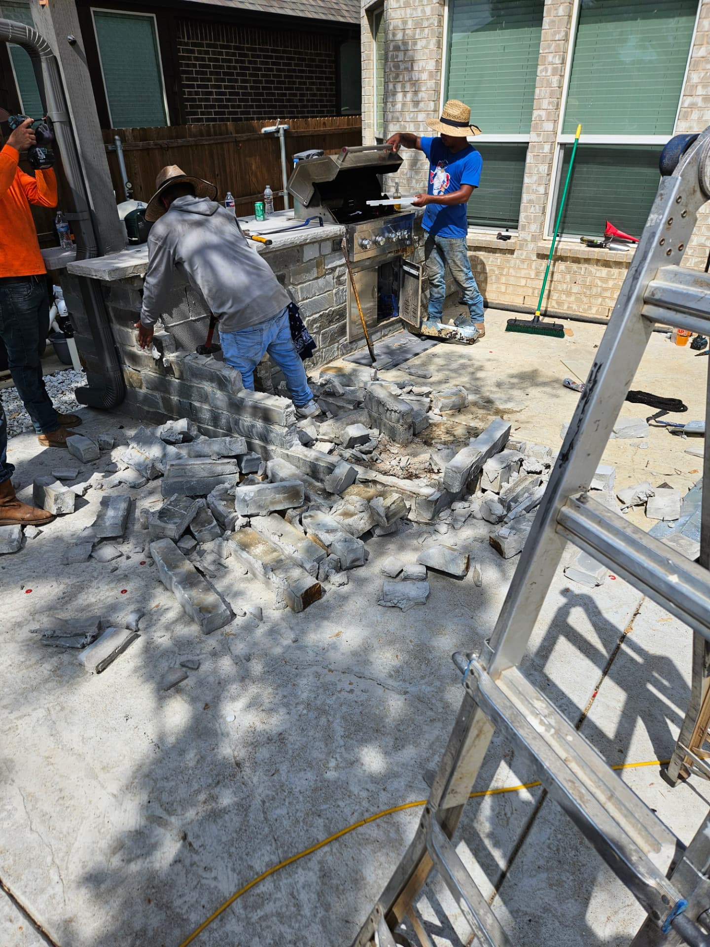W2 Construction crew mid-build on a stone outdoor kitchen and patio on a Johnson County backyard slab