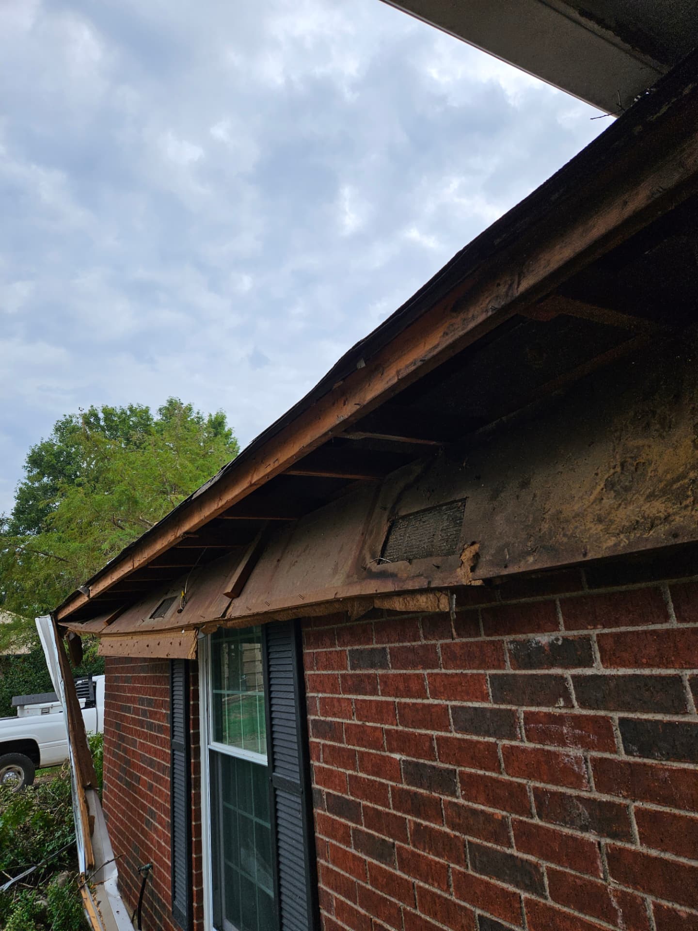 Rotted fascia board and gapped soffit at the eave of a Johnson County brick home