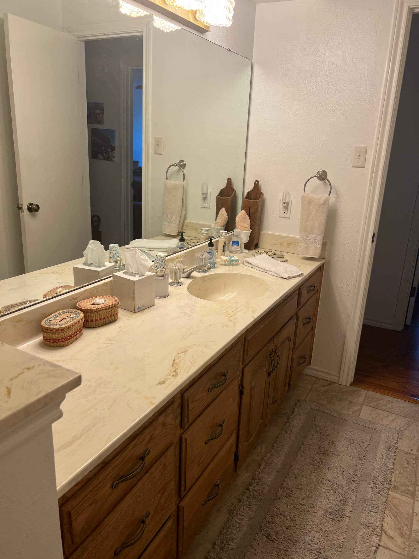 Existing bathroom vanity with wood cabinetry and a full-width mirror before remodeling in Johnson County