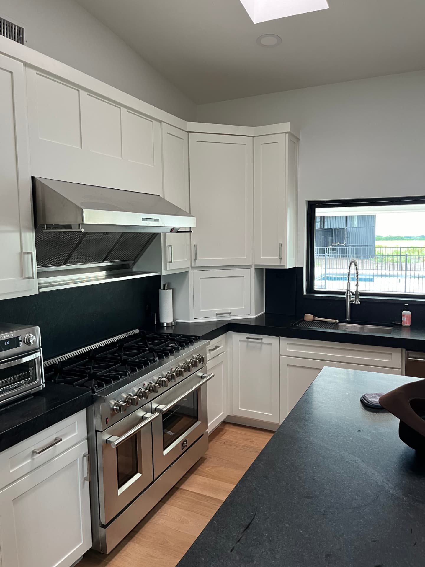 W2 Construction kitchen remodel with white shaker cabinets, dark stone counters, and a pro style range